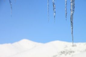 landscape of icicles hang on the house and snowy mountians