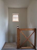 staircase with wooden railing and wooden window in a small building