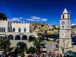 tower among buildings and green palm trees on an island in greece