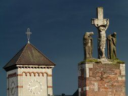 the clock tower and the cross with sculptures