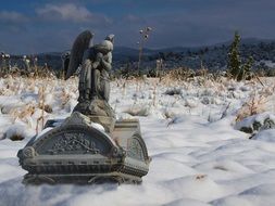 stone sculpture of an angel on a gravestone in a cemetery in winter