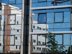 mirroring of white building on glass facade