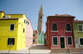 brightly colored house on a background of the bell tower in the Burano island in Venice, Italy