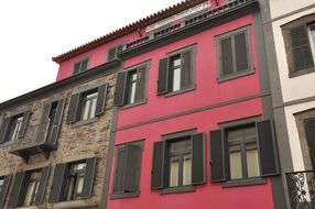 house with a pink wall and wooden windows