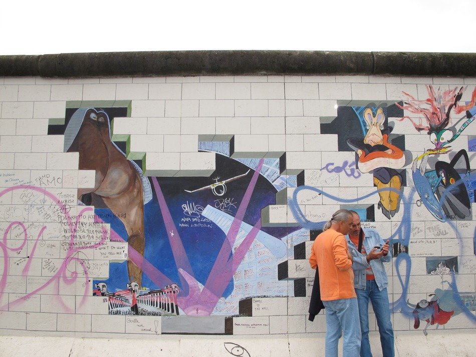 tourists on the background of the east side gallery in Berlin, Germany