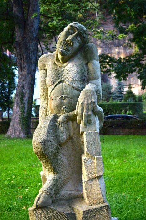 stone figure in the park among the plants