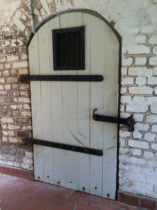 white wooden door with wrought-iron lock in the stone wall