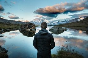 back view of man watching mountains and lake
