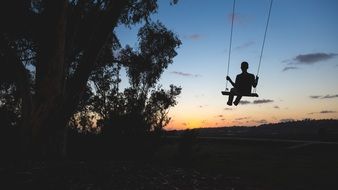 photo of the boy on a swing at dusk