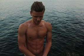 young man with a sports figure on the shore of a pond