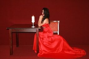 girl in a red dress on a background of burning candle on a table