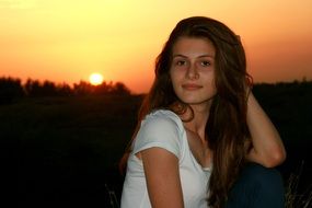 beautiful girl with long hair on a background of orange sunset