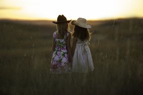 sisters in hats on the summer field