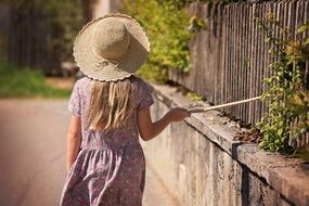 girl knocks on his stick on the fence