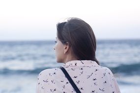 Thinking girl with long dark hair looking at sea horizon