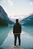young man watching mountain lake