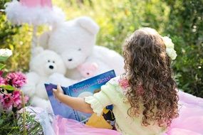 little girl reading book in the garden
