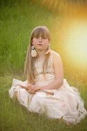 Girl with a flute in the meadow in the glare of the sun