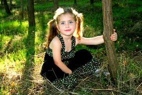 child girl with blue eyes and blond hair on the background of the forest nature