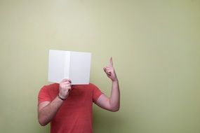 Man in red tshirt with book near the wall