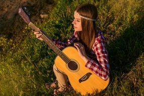 girl with a guitar on a background of summer nature