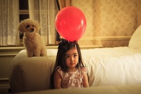 child is holding on a red balloon