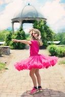 little girl dancing in a bright pink dress