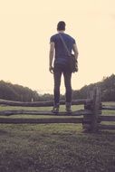 young man standing on wooden fence at countryside