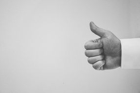 thumbs up hand grey wall