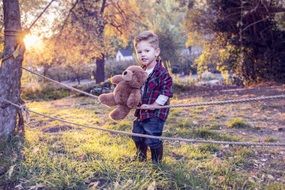 boy shakes a teddy bear on a rope