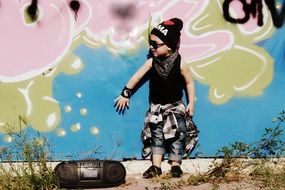 child dressed in the style of hip hop on the background of graffiti