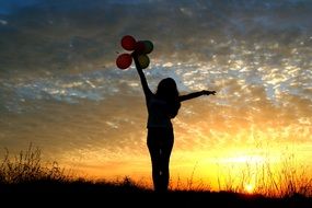 girl with balloons seeing off the sunset