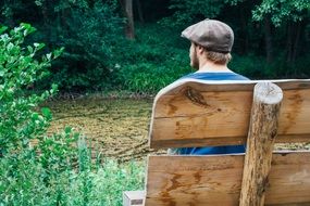 Rear view of a man who sits on a bench among beautiful nature