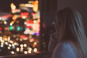 blonde near the window contemplates the night city