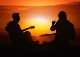 persons playing on a guitars at the sunset