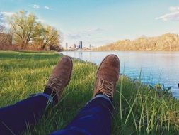A view of the feet of a man in shoes near the water