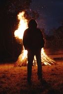 a man stands near a fire at night