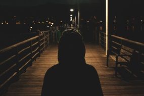Lonely human is walking on a pier at night