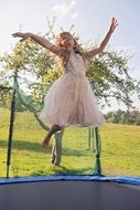 girl in pink dress jumping on trampoline
