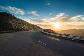 road on a hill against the backdrop of the rising sun