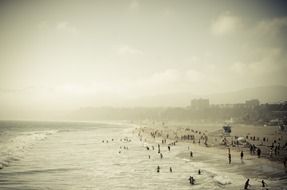 panoramic view of people on a sandy beach in a sunny haze