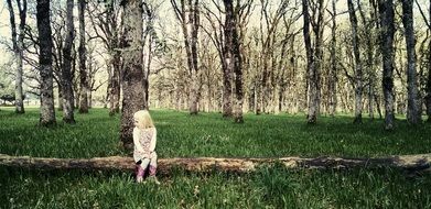 little girl sitting on a tree trunk on a background of the forest nature