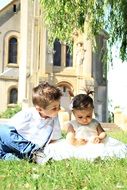 cute children sit on green grass in the park