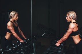 girl trains the muscles near the mirror