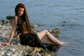 beautiful girl is sitting on the beach in black dress