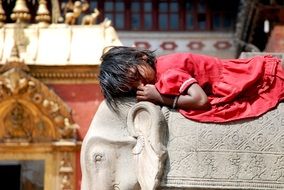 nepal girl lays on back of stone elephant