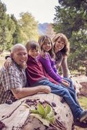 photo of a friendly family on a log in the forest