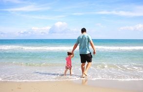 father and daughter walk along the beach