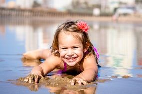 little girl lies on the beach near the sea