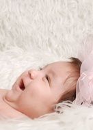 happy baby among white feathers